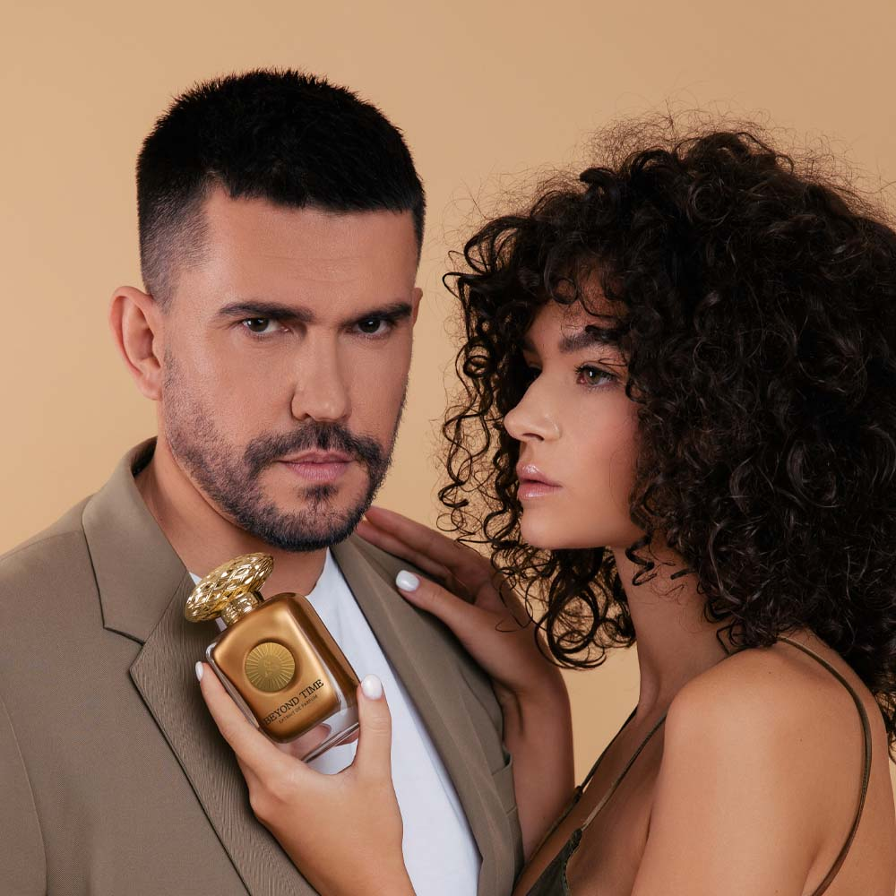 A woman & a man holding Beyond Time by Auraa Desire