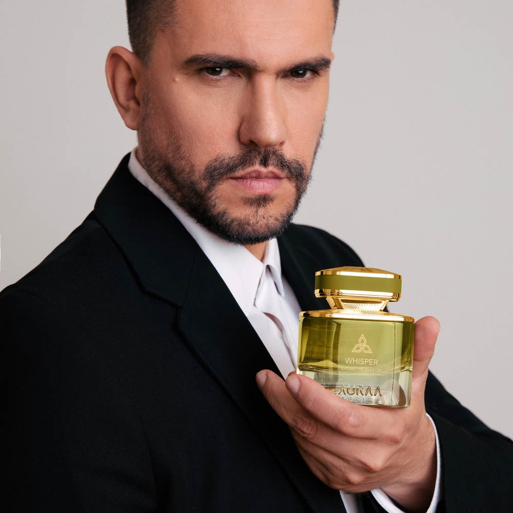 A man wearing a black suit holding a green perfume by Savia Exclusive