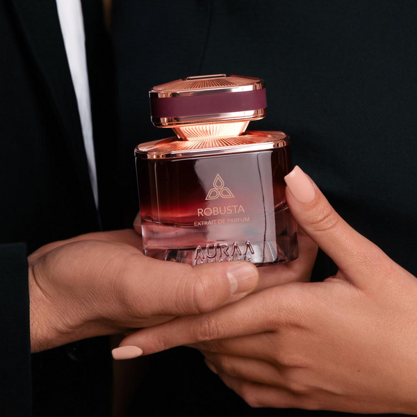 A man & woman holding a maroon perfume bottle by Savia Exclusive